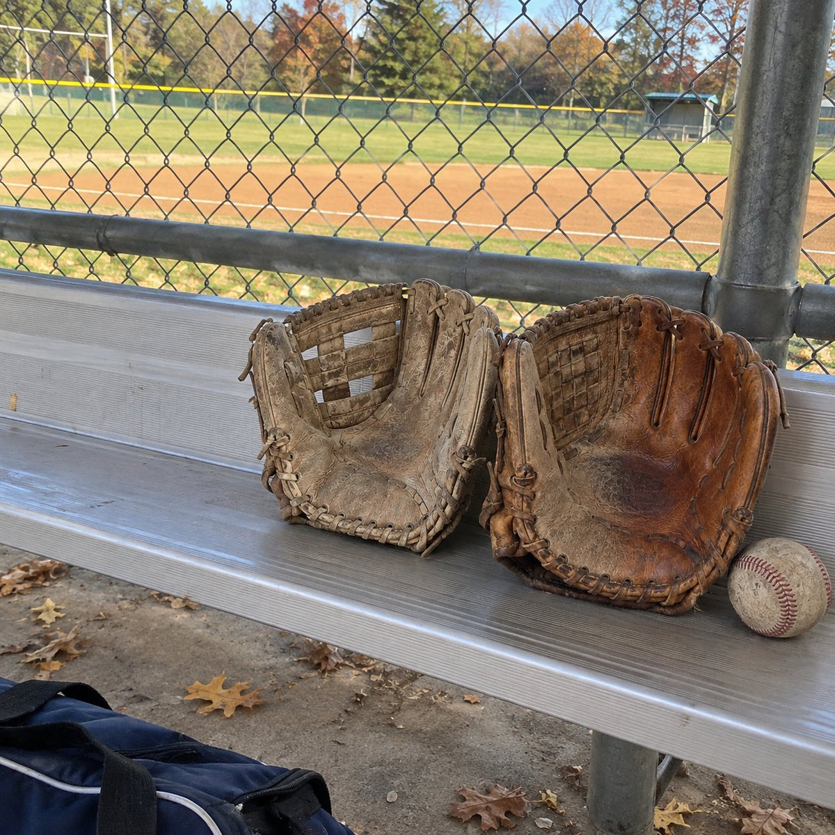 An untreated glove and a treated glove side by side on a dugout bench