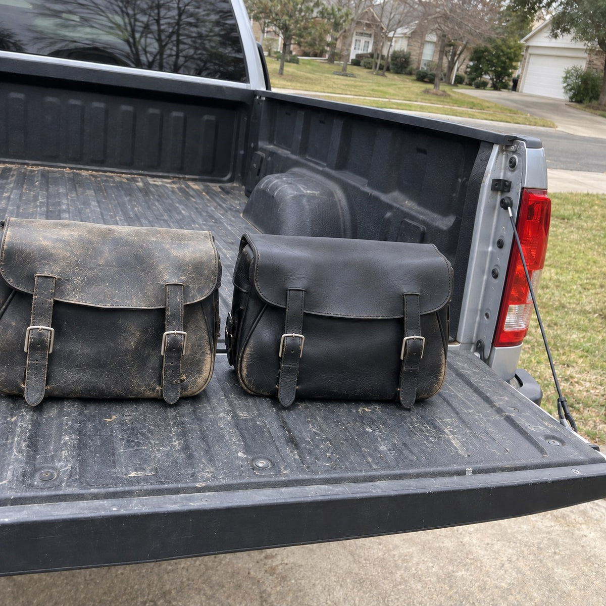 Untreated and treated leather saddlebags side by side on a pickup tailgate