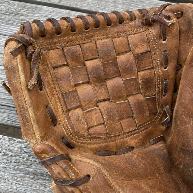 Close-up of a glove's woven web and rawhide laces
